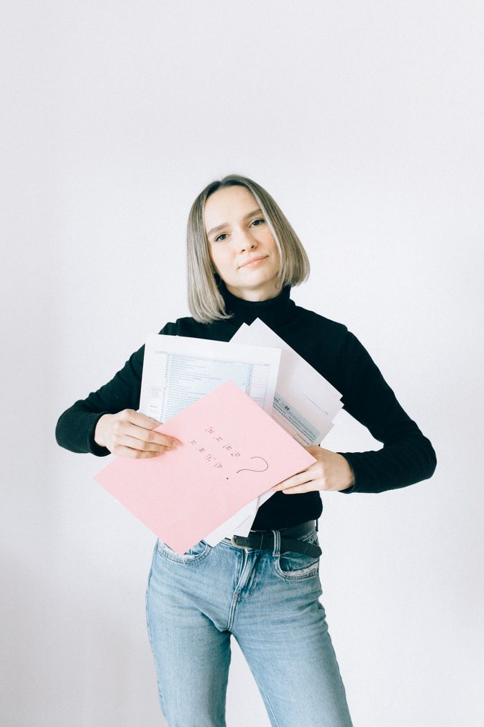 who-we-are Confident woman holding tax documents in casual attire, ready for filing.